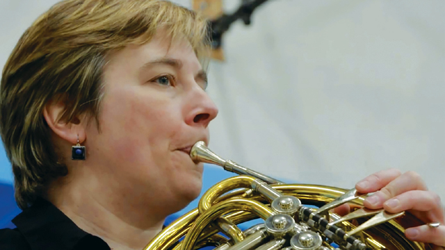 An orchestra member playing the French horn